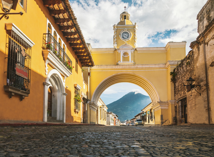 Cobblestone street in Antigua Guatemala with a volcano in the background